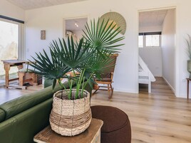 Una habitación con un sofá de cuero verde, una cesta de mimbre con una planta, una mesa de madera y una silla.