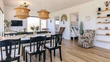 A dining area with a wooden table and chairs, a television, and a view of the outdoors.