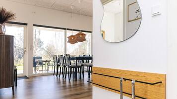 A modern interior with a dining area, wooden flooring, and a large mirror on the wall.