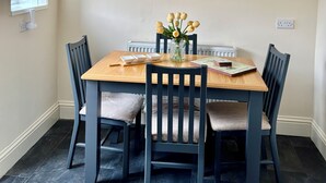 A dining area with a wooden table, six chairs, a vase of flowers, and a black pendant light.