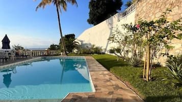 Een buitenzwembad, parasols bij het zwembad en ligstoelen