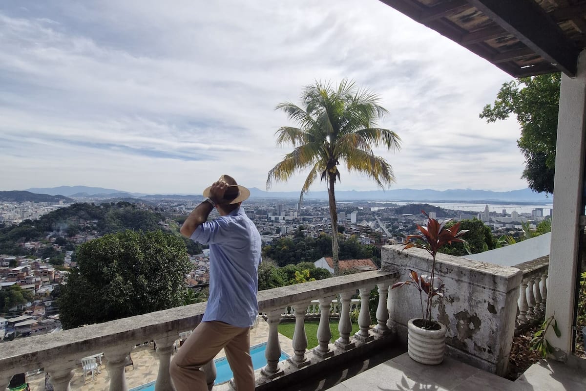 A balcony with a view of a cityscape, a palm tree, and a pool.