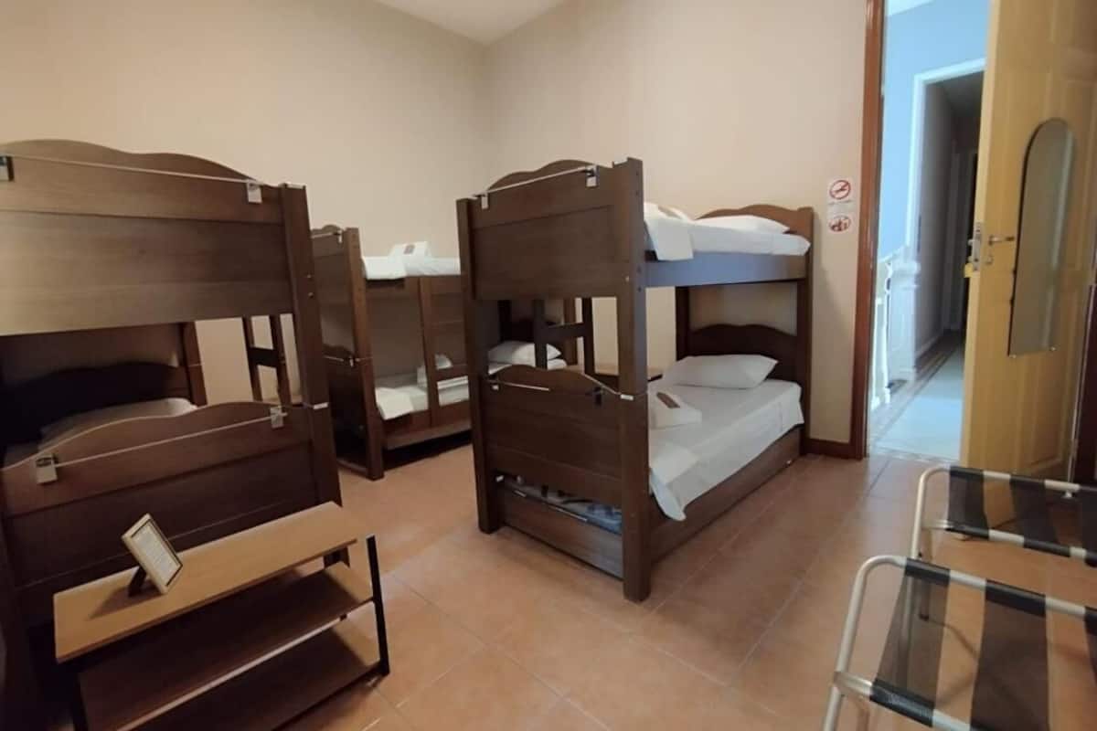 A room with bunk beds, a small desk, and a chair.