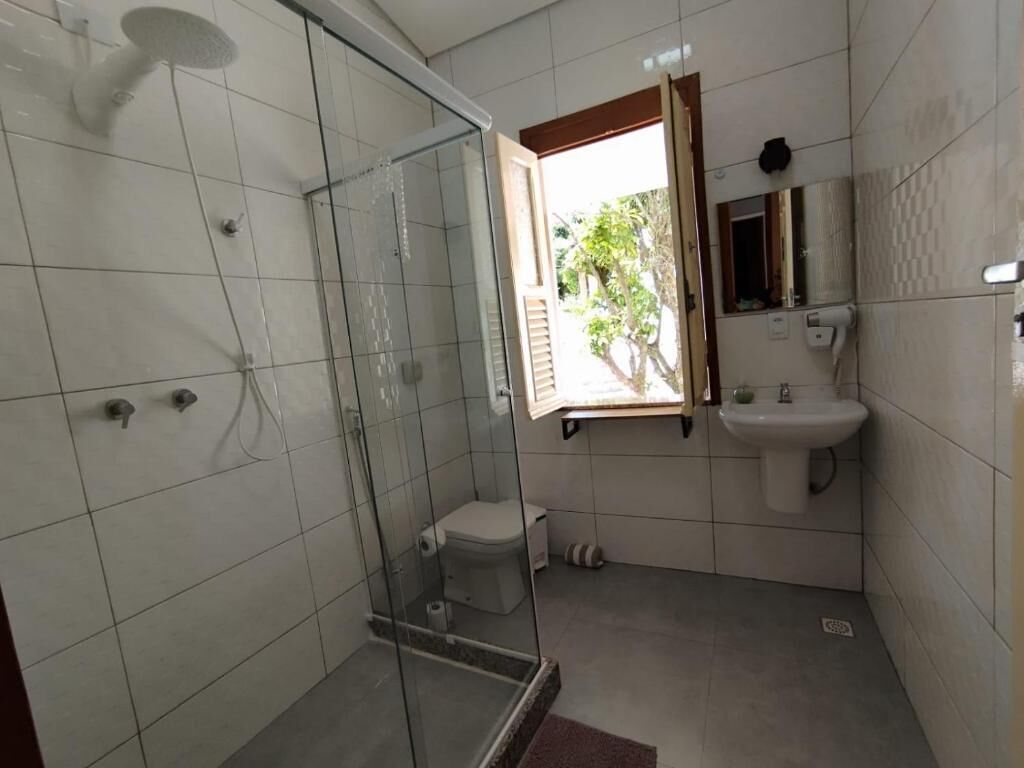 Une salle de bain dotée d’une douche à parois de verre, de toilettes, d’un lavabo et d’une fenêtre laissant entrer la lumière naturelle.
