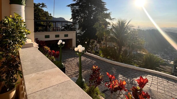 Une terrasse offrant une vue sur le paysage urbain, un bâtiment orné de colonnes et des plantes en pot.