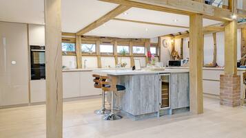 A spacious kitchen with a central island, wooden beams, and a high ceiling.