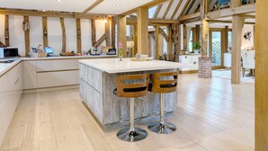 A spacious kitchen with a large island, wooden beams, and a view to the outside. - South Downs Stay - Houghton -  a cottage that sleeps 8 guests  in 4 bedrooms (Houghton)