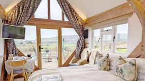 A bedroom with a large bed, a TV, and a view of the countryside. - South Downs Stay - Houghton -  a cottage that sleeps 8 guests  in 4 bedrooms (Houghton)