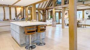 A spacious kitchen with a large island, wooden beams, and a glass staircase. - South Downs Stay - Houghton -  a cottage that sleeps 8 guests  in 4 bedrooms (Houghton)
