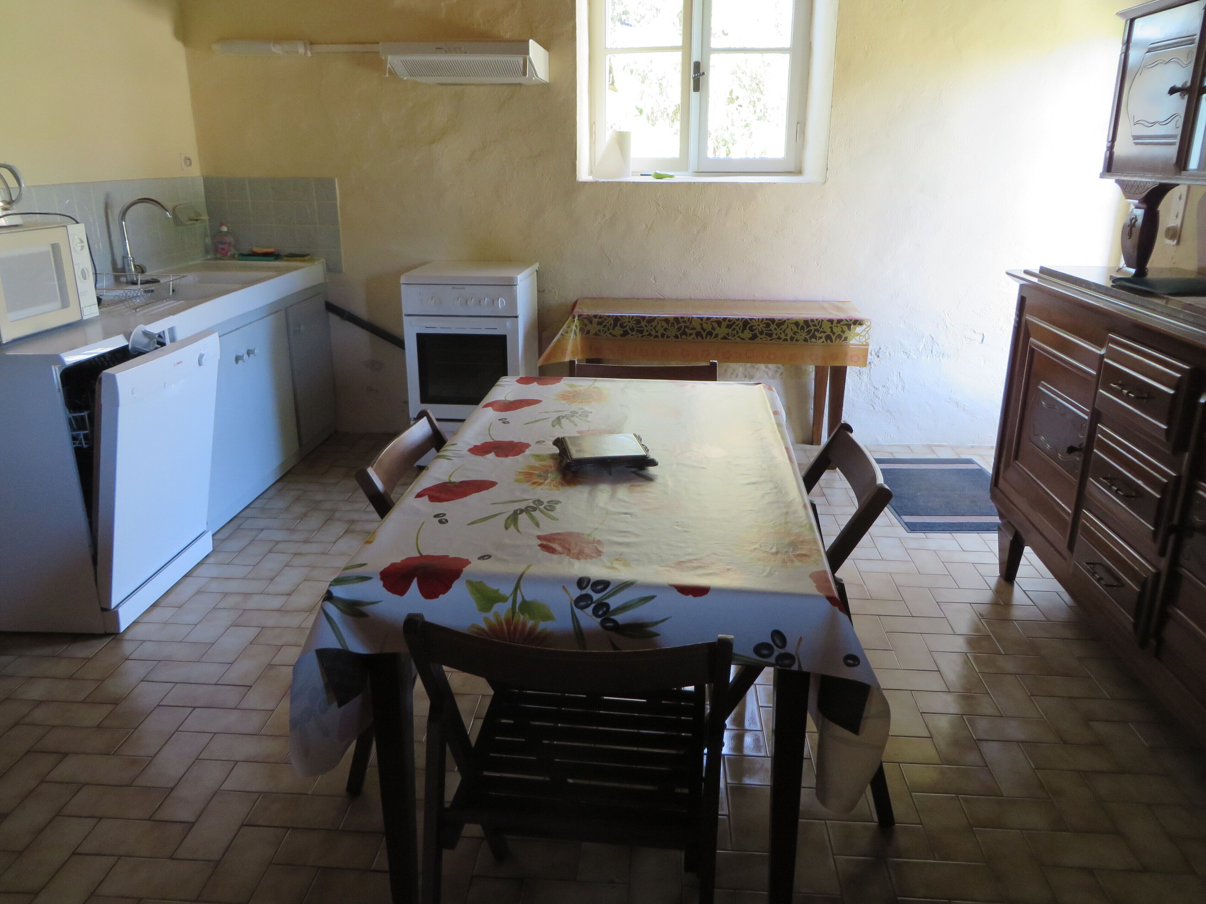 Una cocina compacta con mesa, sillas, refrigerador, estufa y un armario de madera.