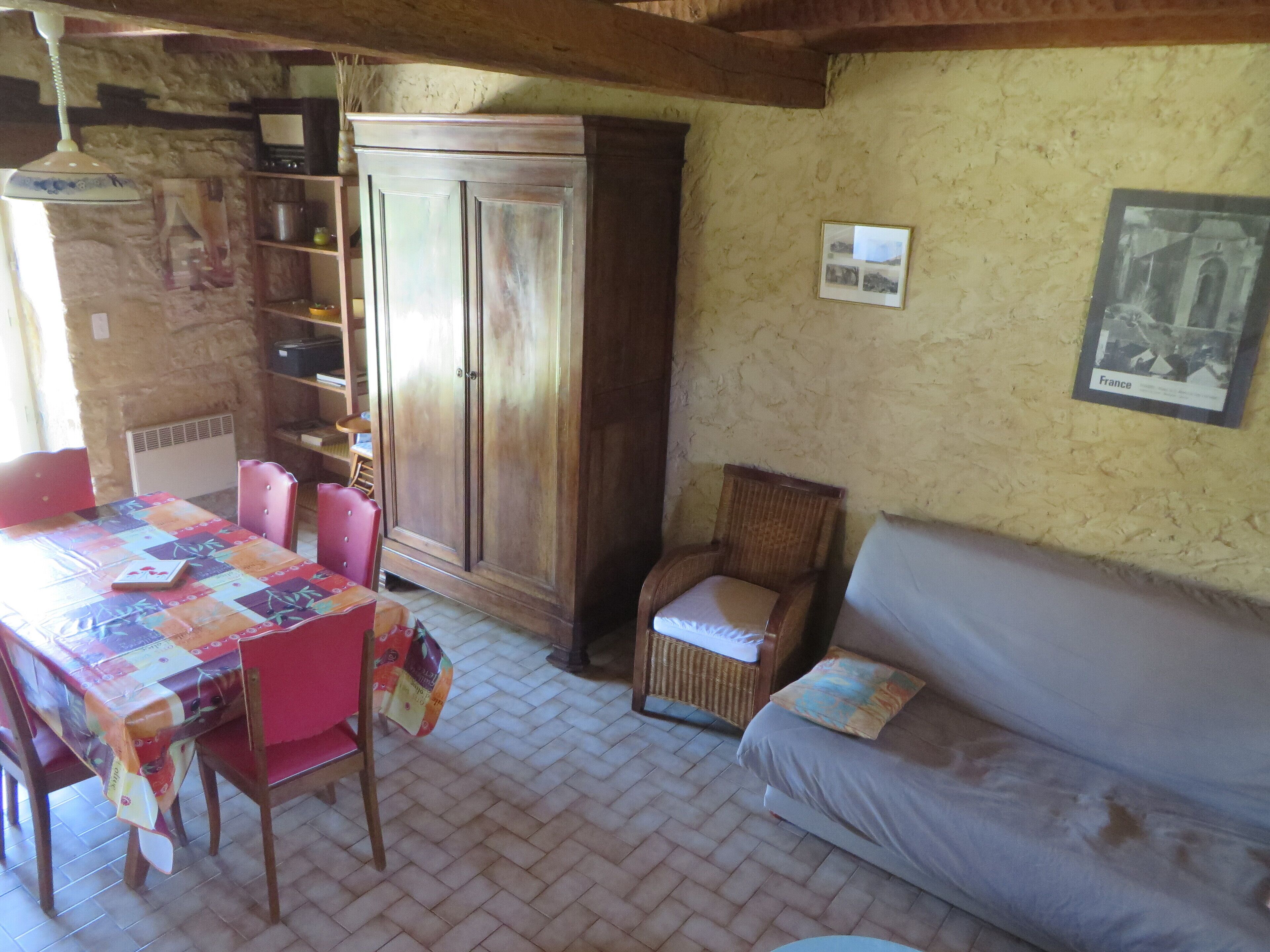 Une pièce chaleureuse comprenant une table à manger, des chaises, un buffet, un fauteuil en osier et un canapé.