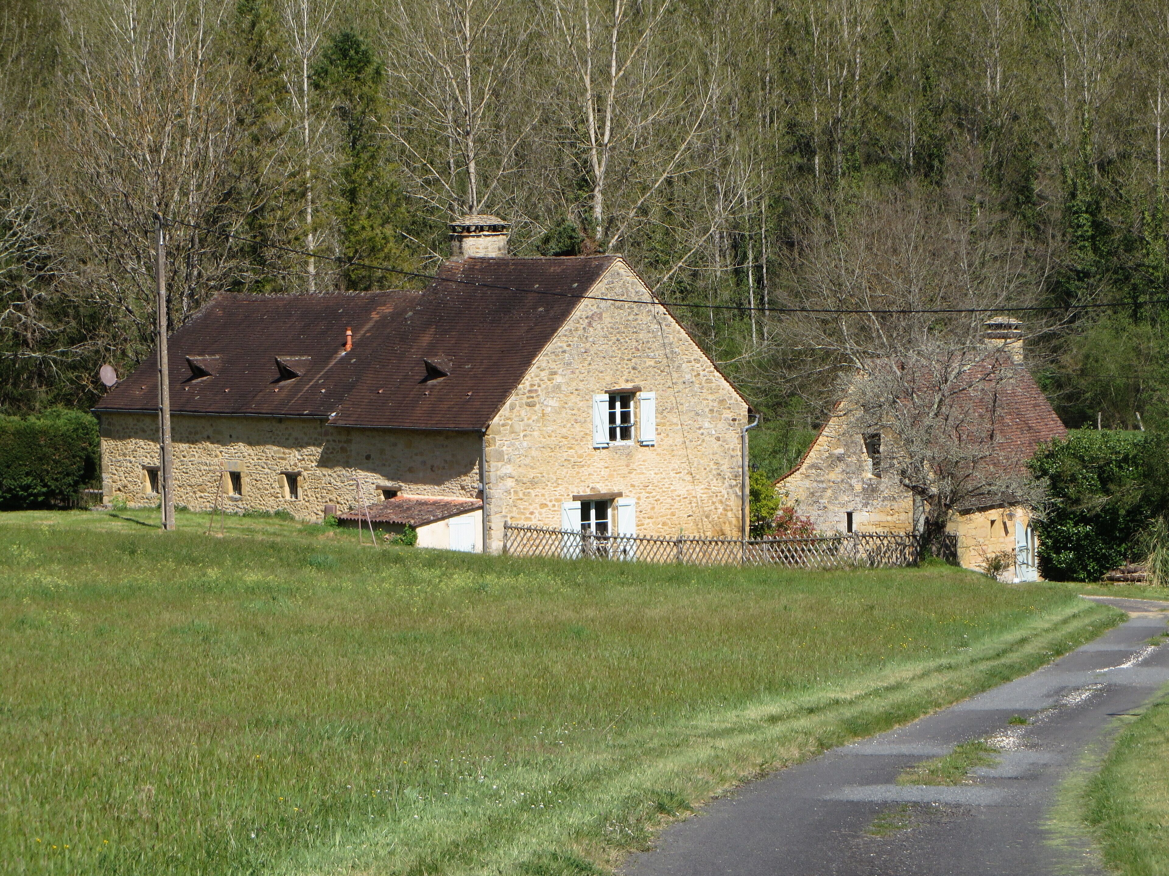 A stone house with a sloped roof, a small window, and a chimney.