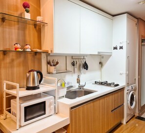 Cocina compacta con microondas, hervidor, pileta y lavadora integrada.