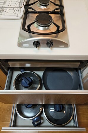 A kitchen with a stove and a drawer containing pots and pans. - KUMA HOUSE MAPO (Mapo gu)