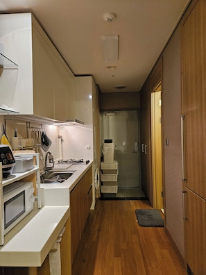 A narrow kitchen with a microwave, sink, and cabinets.