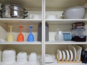 A kitchen with white cabinets, a stainless steel pot, and various kitchenware including vases and plates. - KUMA HOUSE MAPO (Mapo gu)