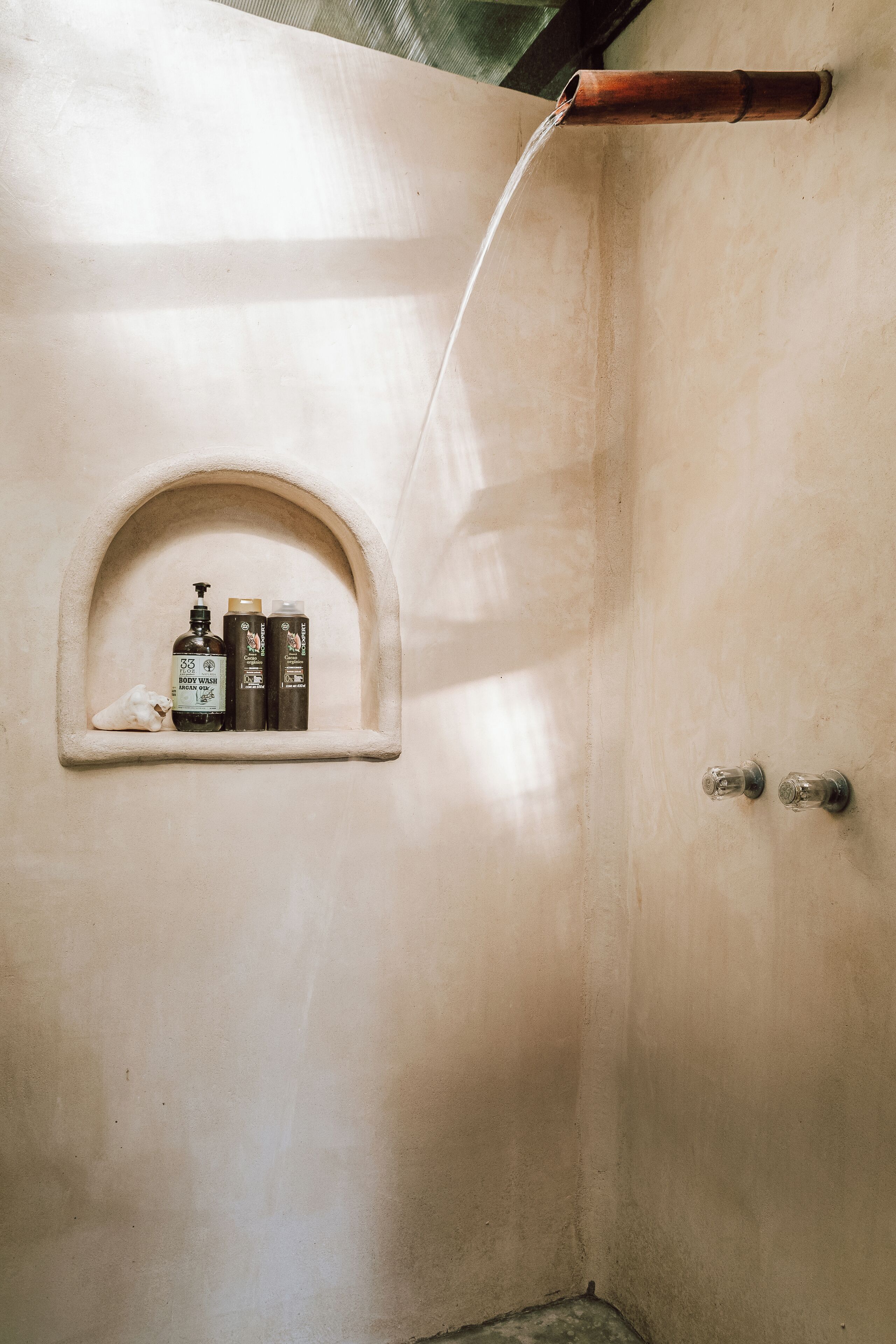 Un baño con ducha, estante con artículos de aseo y toallero.