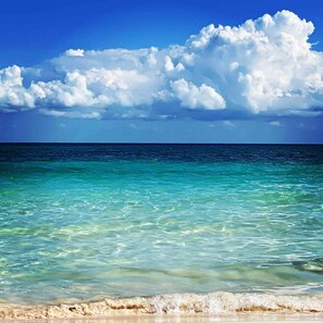 A beach with clear turquoise water and a sandy shore under a bright blue sky with fluffy clouds. - Casa Arkaana Eco Retreat (Tulum)