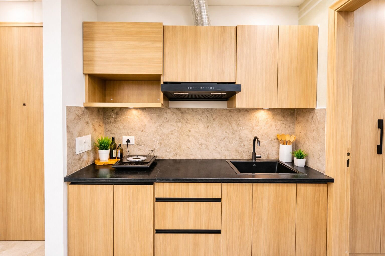 Une cuisine moderne avec des meubles en bois, un plan de travail noir, une cuisinière encastrée et un évier.