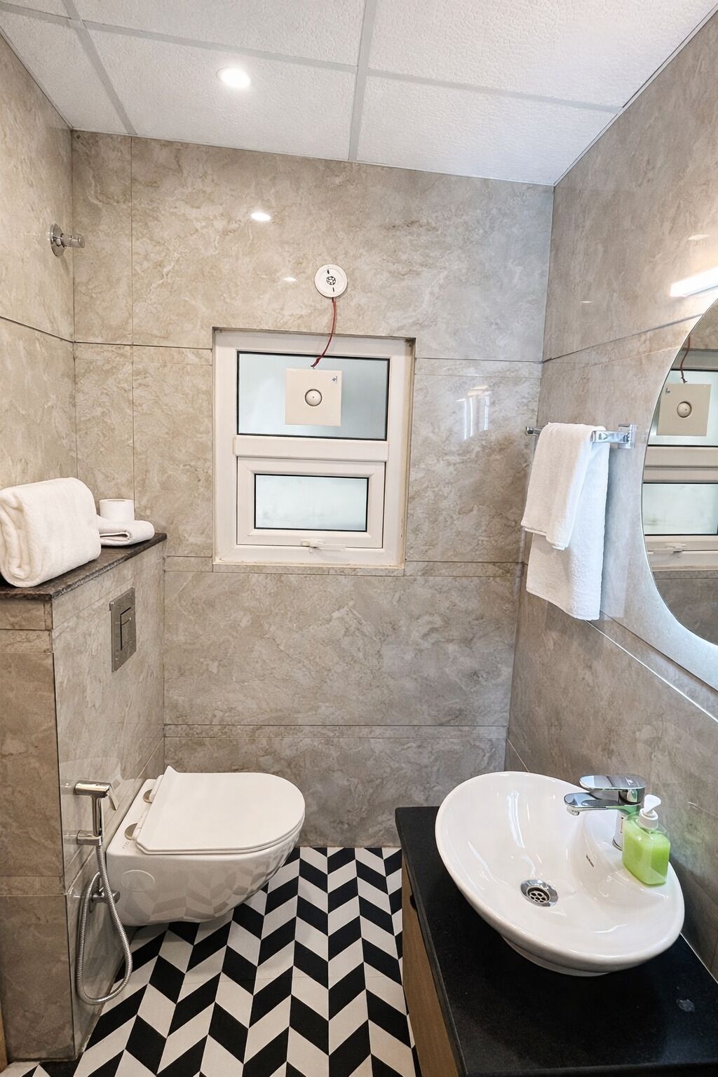 A bathroom with a toilet, bidet, and sink, a mirror, and a towel rack.