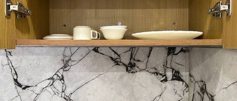 A kitchen with a marble countertop and wooden cabinets.