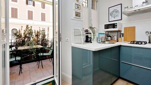 A modern kitchen with a glass door leading to an outdoor seating area. - Raffinato appartamento con piccolo giardino al Vaticano  (ROMA)
