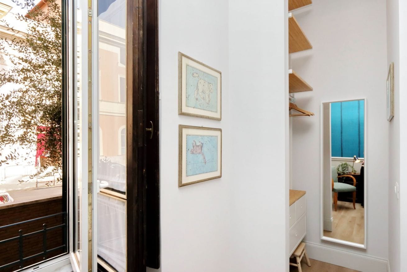 A room with a large window, a door, and two framed pictures on the wall.