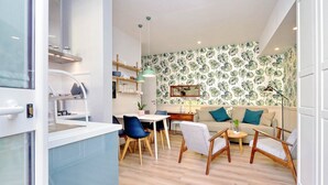 A modern living room with a dining area, featuring a kitchen in the background, wooden flooring, and tropical wallpaper. - Raffinato appartamento con piccolo giardino al Vaticano  (ROMA)
