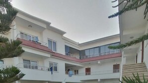 A multi-story building with a courtyard, outdoor seating area, and a staircase. - İLKER APART OTEL (Silifke)