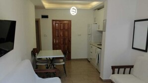 A compact living space with a sofa, a dining table, and a kitchenette. - İLKER APART OTEL (Silifke)