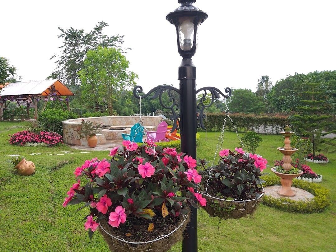 A garden with a fountain, a lamp post, and a gazebo.