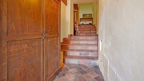 Une porte en bois, un escalier recouvert de carreaux rouges et un mur vert clair.