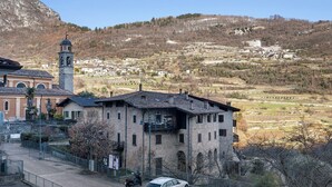 Un bâtiment doté d’un clocher, d’une cour pavée et offrant une vue sur un village vallonné.