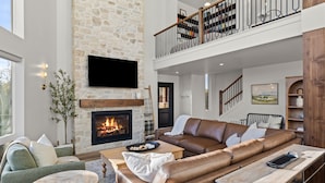 A spacious living area with a stone fireplace, leather sofas, and a wooden coffee table. - Zion East Luxury | Private Hot Tub & Fire Pit (Orderville)
