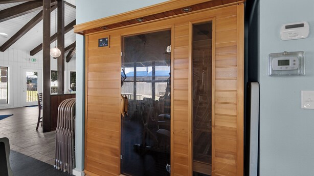 A wooden sliding door with a glass panel, a control panel, and a thermostat on the wall. - Hidden treasure minutes from Pensacola Beach with large pool area! (Gulf Breeze)