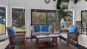A covered patio with a sofa, two chairs, a coffee table, and a clock on the wall. - Hidden treasure minutes from Pensacola Beach with large pool area! (Gulf Breeze)