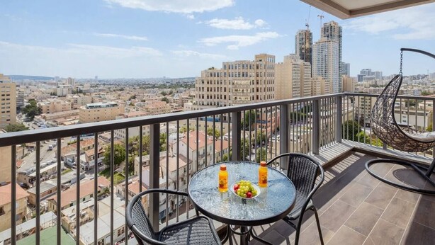 A balcony with a glass table, two chairs, and a hanging chair. - 2 BR Apartment in Savyoney Tower (w/ safe room) (Jerusalem)