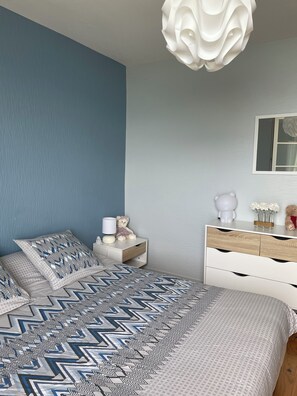 Ein Schlafzimmer mit Bett, Nachttisch, Kommode und einer Pendelleuchte.