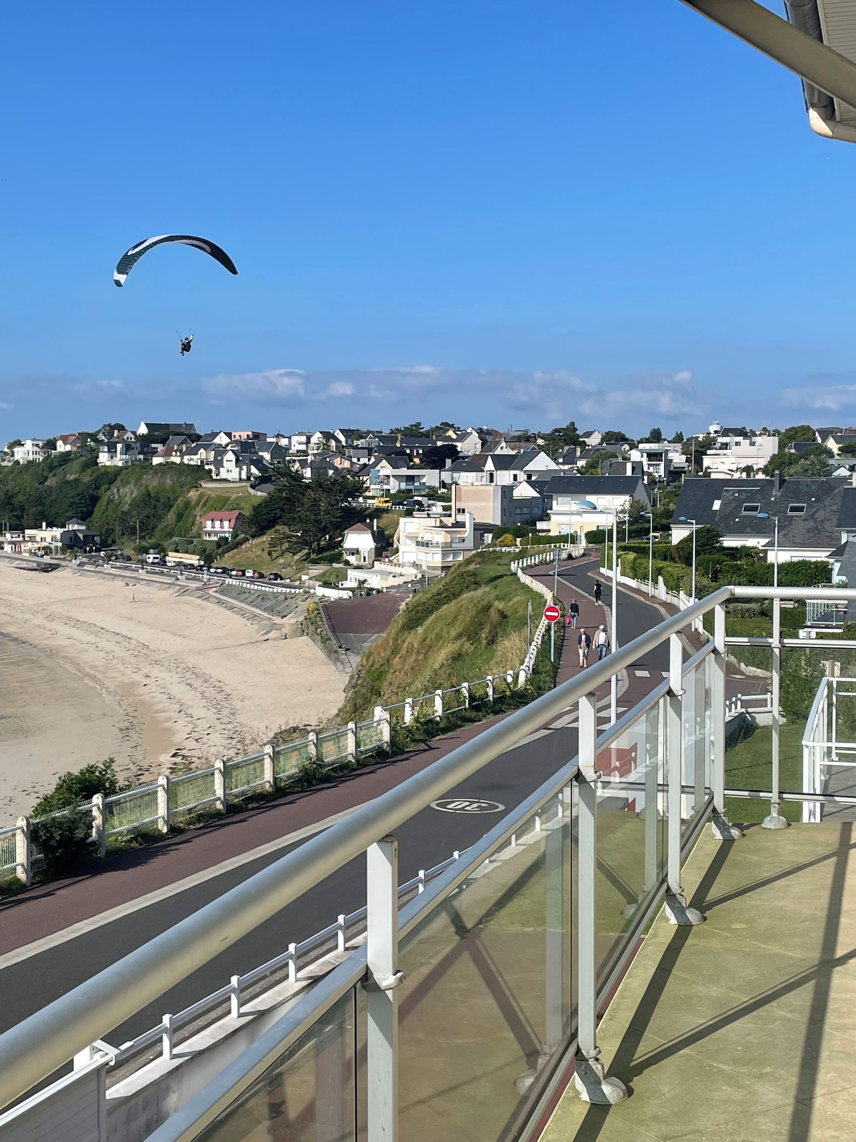 Une ville côtière avec une plage, des maisons et une route dotée d’un chemin piétonnier.