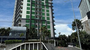 A tall, modern building with a prominent vertical design, featuring multiple balconies and a mix of glass and solid panels. - Room-sea View Room - Infinity Pool Near (Pattaya)