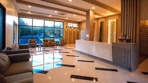 A hotel lobby with a reception desk, seating area, and large windows. - Room-sea View Room - Infinity Pool Near (Pattaya)