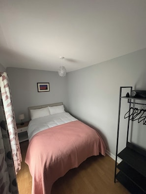 A bedroom with a bed, a nightstand, a hanging light fixture, a framed picture on the wall, and a black shelf with items. - Spacious Private Country House - king beds - extensive parking (Omagh)