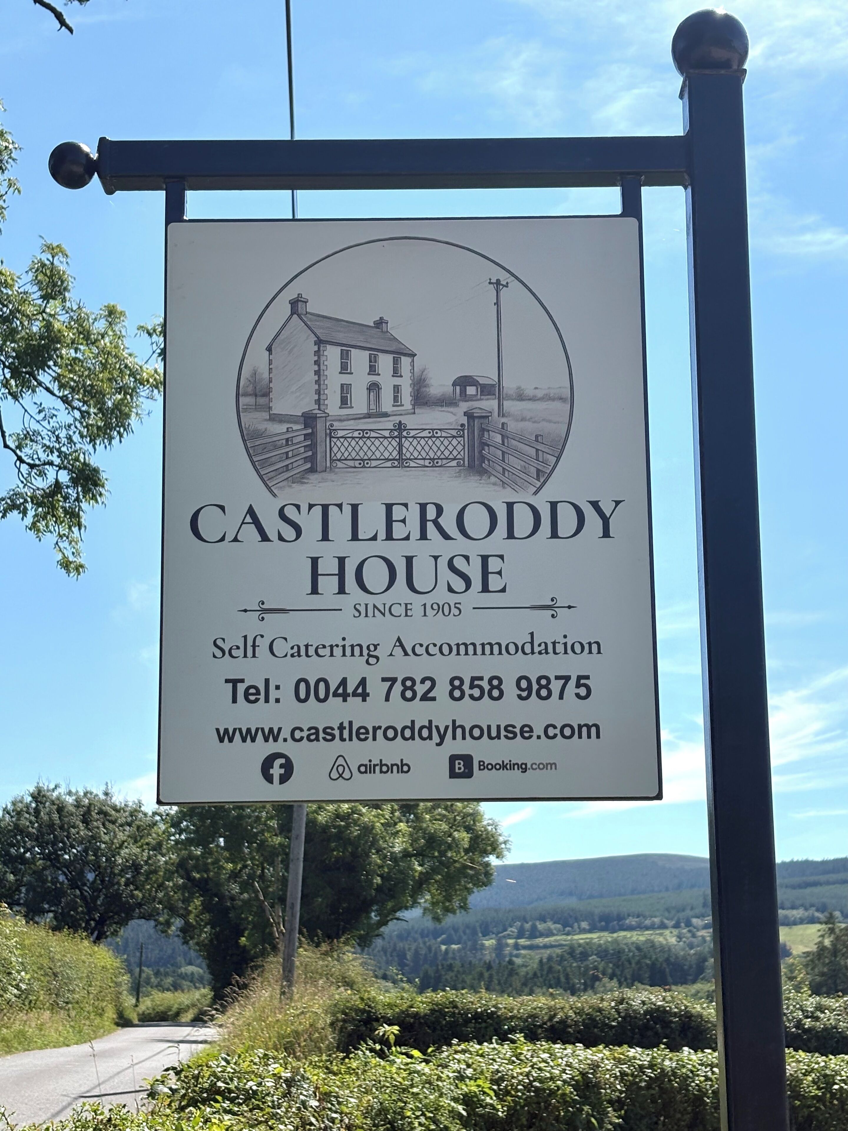 A sign for Castleroddy House, a self-catering accommodation since 1905, with contact details and booking options.