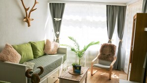 Ein gemütliches Wohnzimmer mit einer Couch, einem Sessel, einem Couchtisch und einem dekorativen Geweih an der Wand.