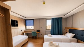 A hotel room with two beds, a desk, a chair, and a window with curtains. - Mooncity Hotel & Boardinghouse  (Düsseldorf)