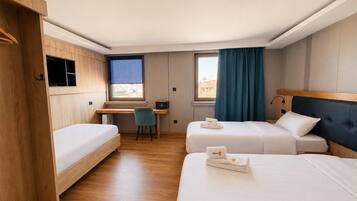 Habitación de hotel con dos camas, un escritorio, una silla y una ventana con cortinas.