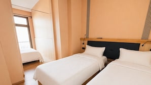 A hotel room with two beds, a wooden headboard, a window, and a balcony. - Mooncity Hotel & Boardinghouse  (Düsseldorf)
