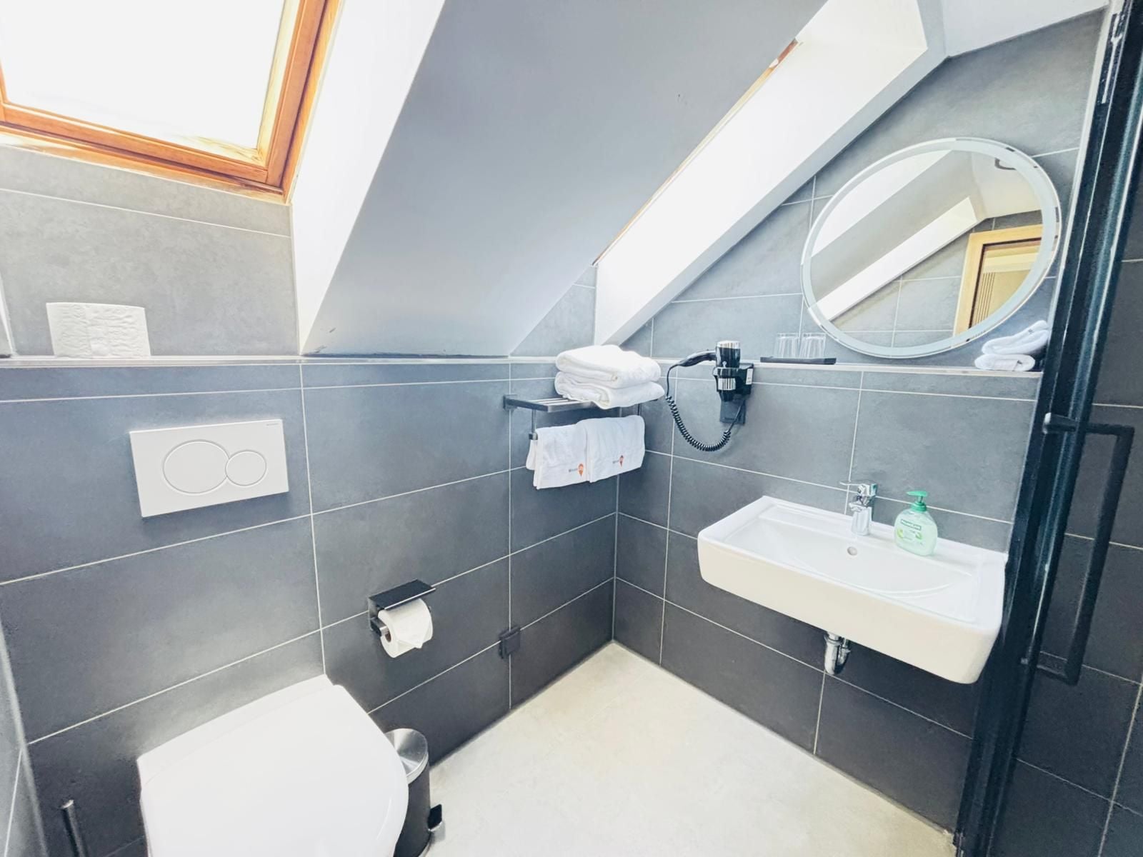 A modern bathroom with a toilet, sink, towel rack, and a mirror.