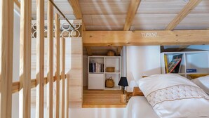 A wooden-framed room with a bed, a shelf with books, and a basket. - Studio "Maya" with Private Terrace, Shared Garden, and Wi-Fi (Le Puy-Sainte-Réparade)