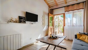 A modern living room with a television, a bookshelf, a sofa, and a dining table. - Studio "Maya" with Private Terrace, Shared Garden, and Wi-Fi (Le Puy-Sainte-Réparade)
